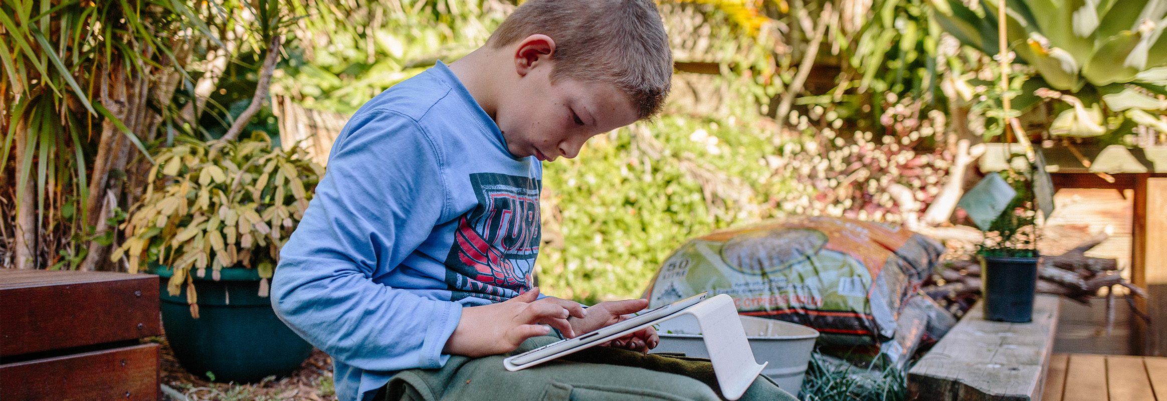 Young boy sitting outside using iPad