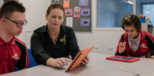 Teacher teaching two children using iPad
