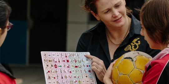 Young girl with soccer ball learning with core words board