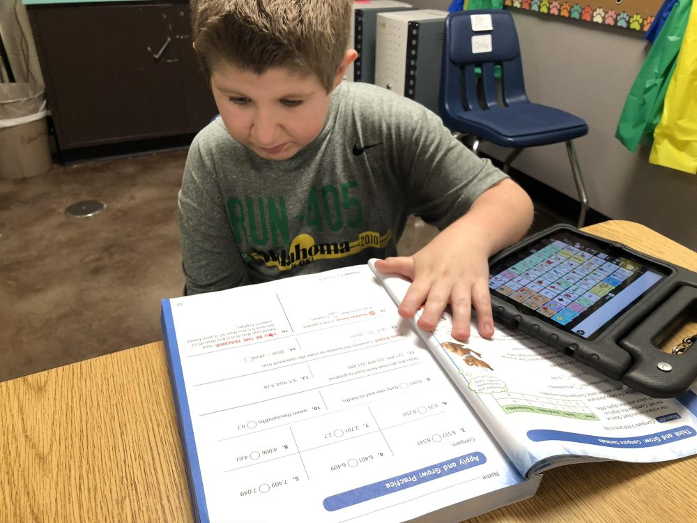 The author's son using a workbook and Proloquo2Go on an iPad