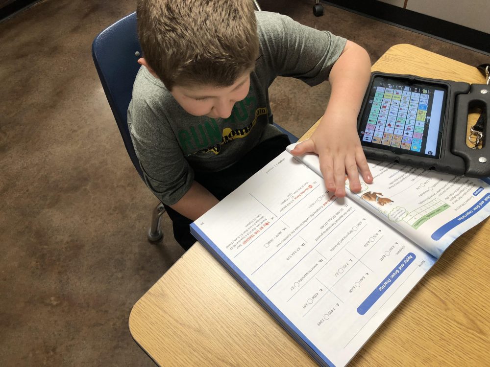 The author's son using a workbook and Proloquo2Go on an iPad