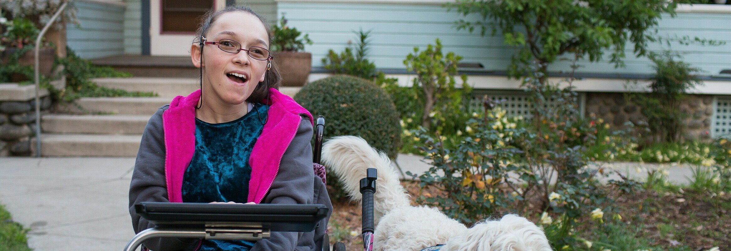 Elina, een witte vrouw in een rolstoel met een iPad en een hond aan haar zijde