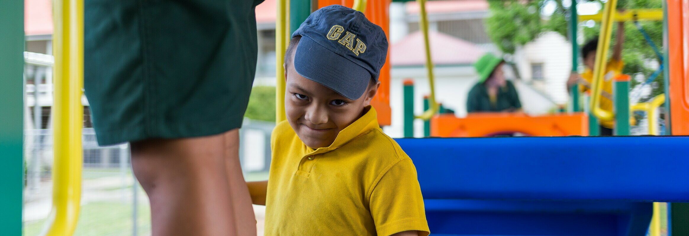 Monty, a young Samoan boy on a playground, smiling at the camera