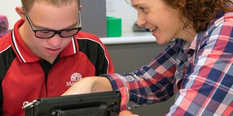 Boy learning and communicating through iPad with teacher