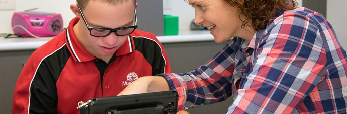 Boy learning and communicating through iPad with teacher