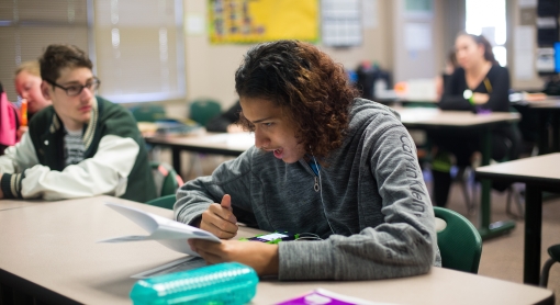 A boy looking at a sheet of paper in a classroom