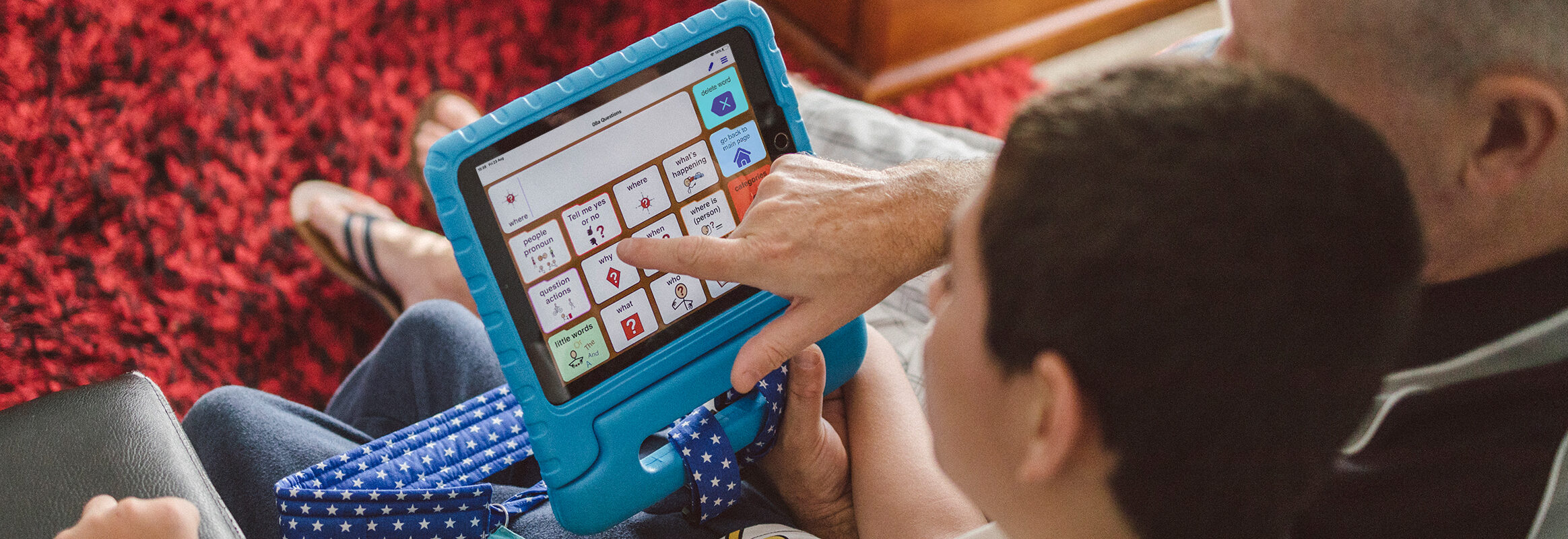 Son with father using simPODD on iPad