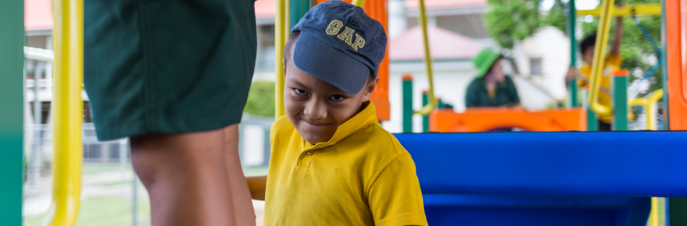 Monty, a young Samoan boy on a playground, smiling at the camera