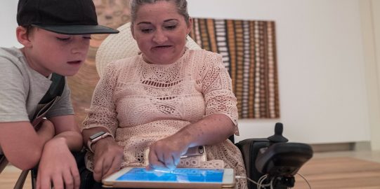 Lisa writes on her iPad while her son reads what she writes