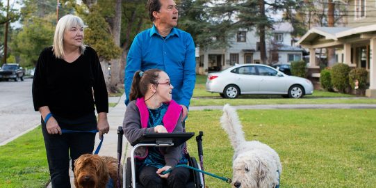 Père, mère et enfant qui promènent leur chien, tous regardant à gauche