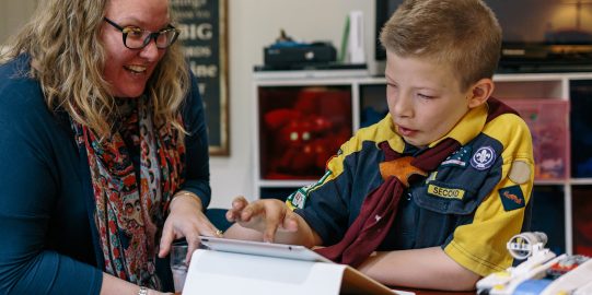 Young boy learning with iPad with his mother