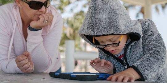 Young boy using iPad outside