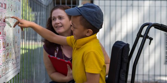 Young boy pointing to a Core Words board