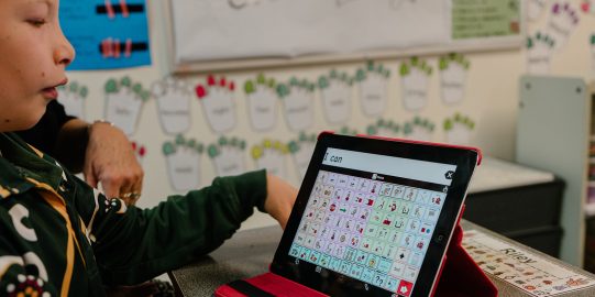 Young boy in classroom learning with iPad AAC System