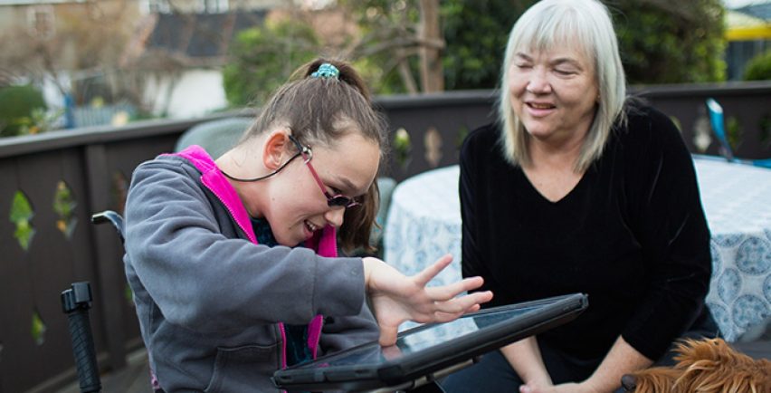 Elina en een andere vrouw die buiten zit en interactie heeft met een iPad