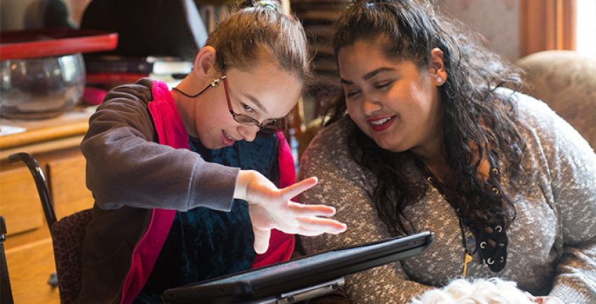 Elina et une autre femme assise à l'intérieur et interagissant avec un iPad