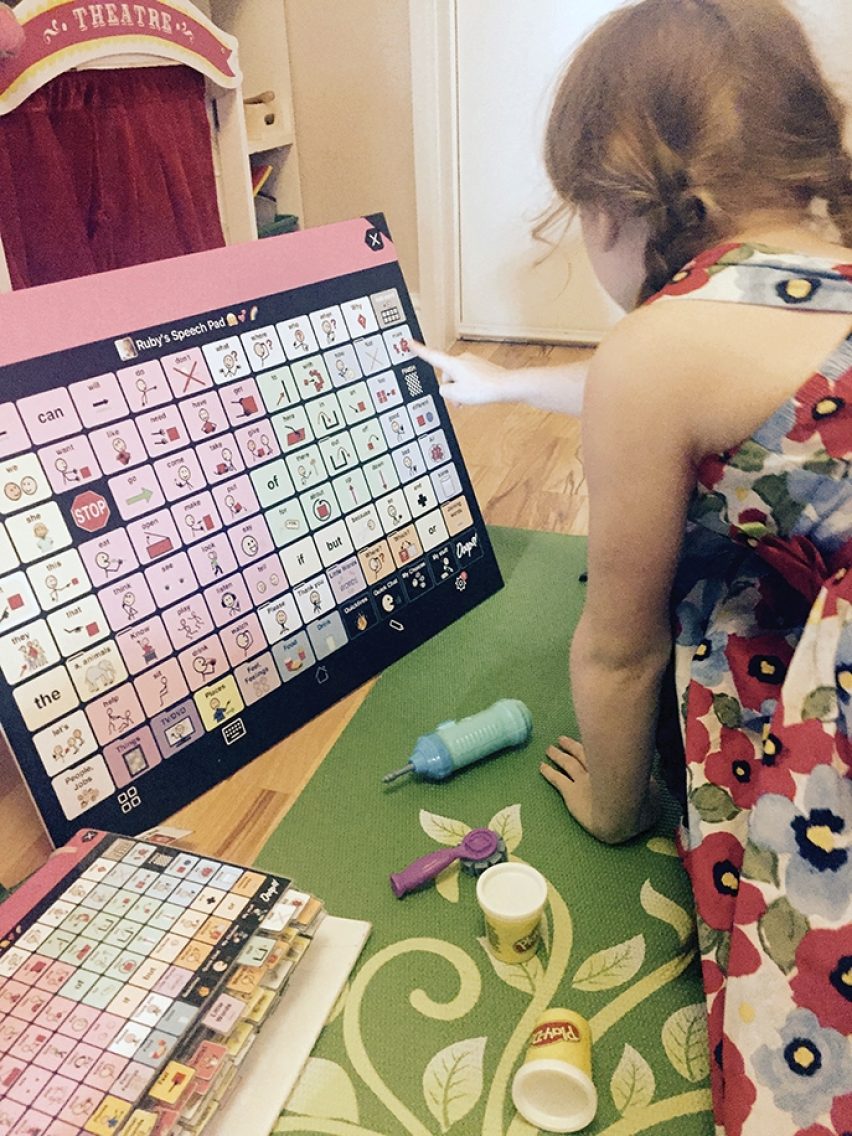 Ruby girl playing with a large Core Word board and Playdoh