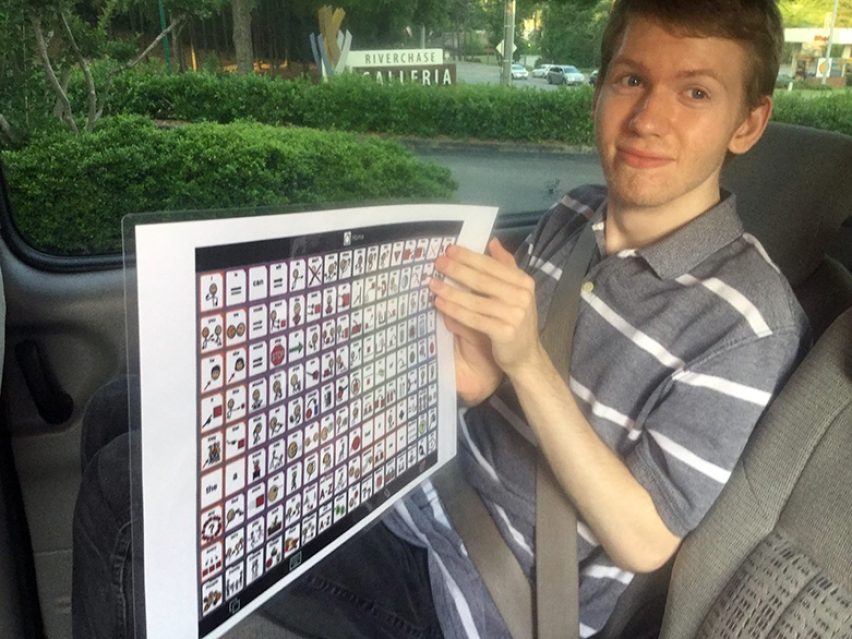 A teenager holding a laminated Core Word Board in the car