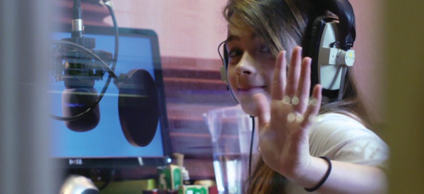 Jeune fille avec un casque audio et un micro faisant coucou