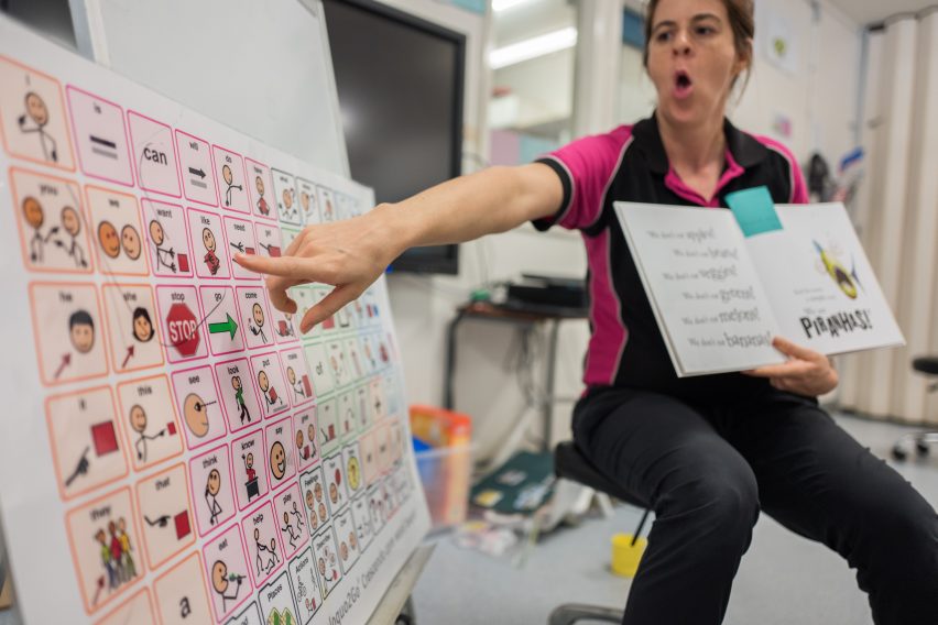 Teacher Pointing To Model Words On Core Word Poster In Classroom