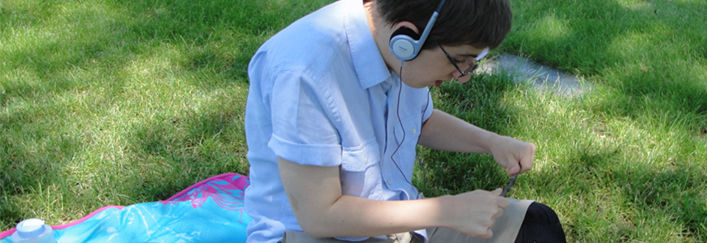 Boy on grass field listening through headphones