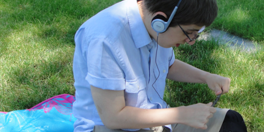 Boy on grass field listening through headphones