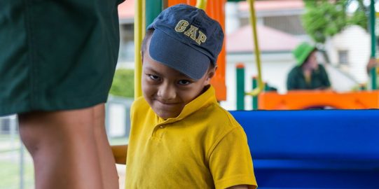 Monty, een jonge Samoaanse jongen op een speelplaats, glimlachend naar de camera