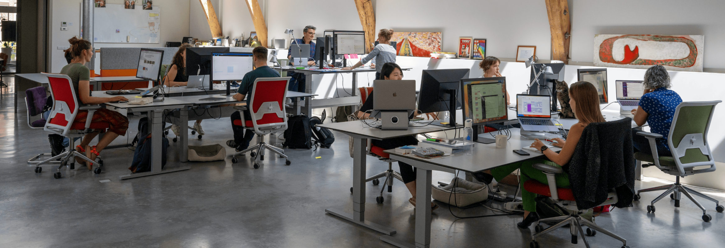 A view of the AssistiveWare office with people working behind desks.