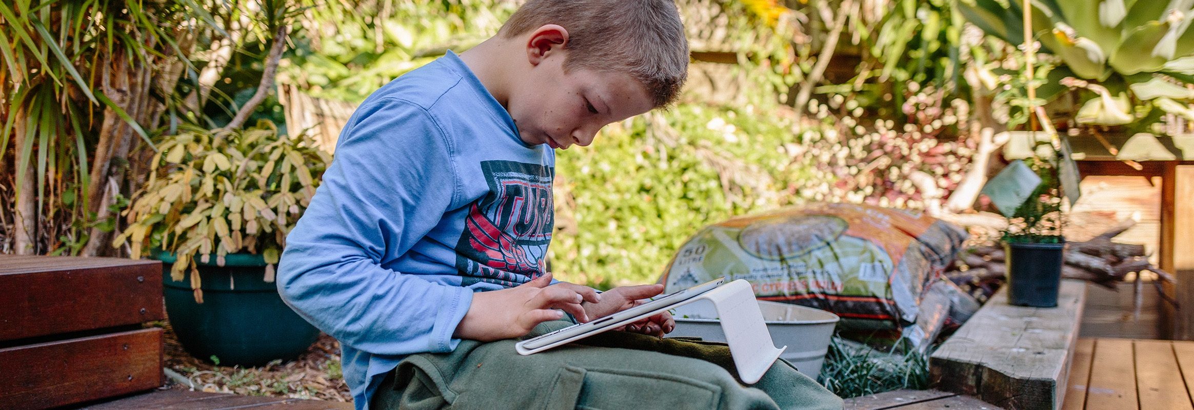 Garçon dans un jardin avec iPad